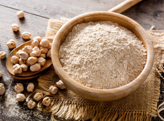 Chickpea flour in wooden bowl on wooden table
