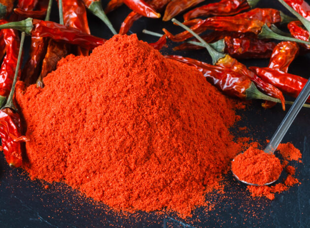 Cayenne red pepper powder in white bowl over wooden background