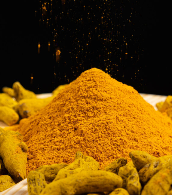 Turmeric powder and dried turmeric root on a black background Turmeric powder and dried turmeric root on a black background.